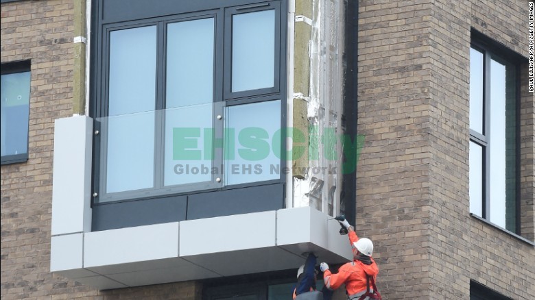 Workers remove panels of external cladding from the facade of a building in the Wythenshawe area of Manchester, northwest England.