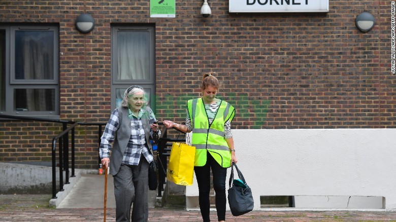 A council worker helps a resident leave Dorney Tower residential block on the Chalcots Estate in north Lo<em></em>ndon on June 25, 2017.
